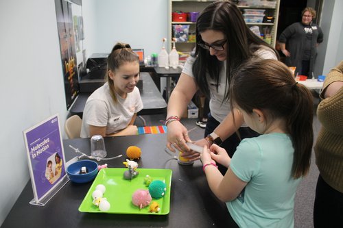 college students working with young children at a museum.