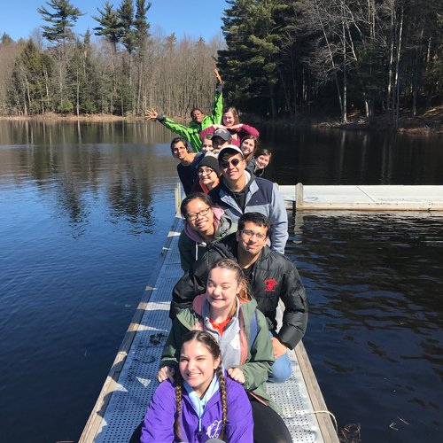 Students posing for picture on a dock on a lake.