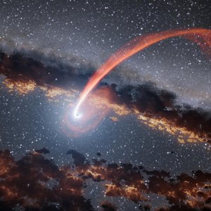 This illustration shows a glowing stream of material from a star as it is being devoured by a supermassive black hole in a tidal disruption flare.