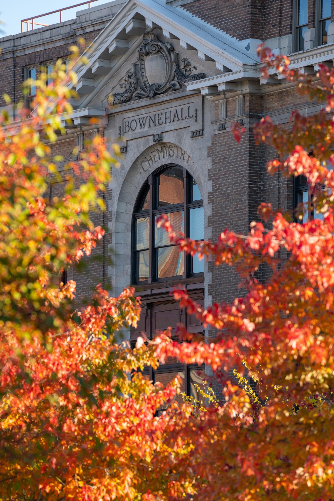 Exterior of Bowne Hall with leaves in the foreground.