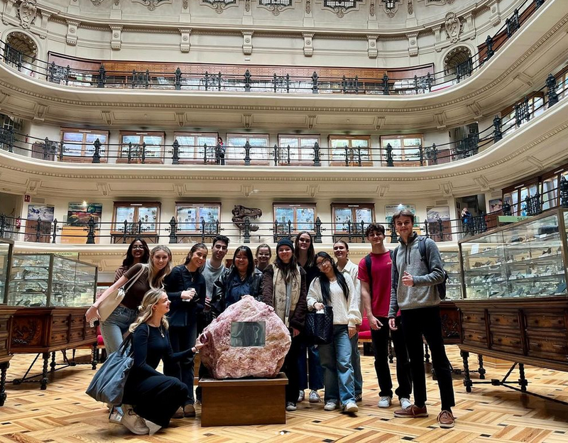 A group of students standing around a mineral in a museum.
