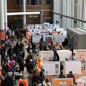 Wide shot of students, faculty and guests gathered in a large atrium at the undergraduate research festival.