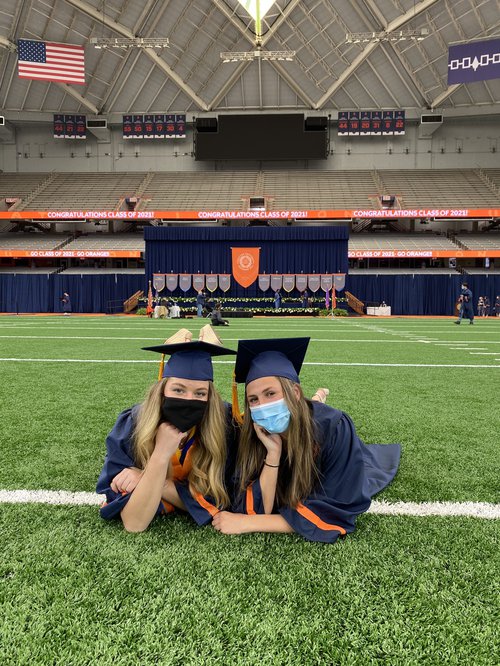 Two girls posing in their graduation caps and gowns on The Stadium turf.