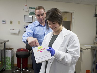 Aaron Wolfe shows Ellie Iumen what plasmids to use for a protein production run at Ichor Therapeutics.