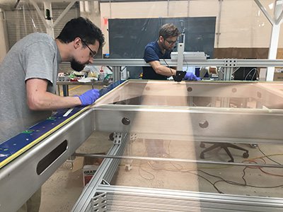 Posdoc Pip Hamilton (foreground) and Bhat work on part of an anode plane assembly, or APA, at Yale. 
