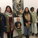five adults and one child standing next to wall hung artwork