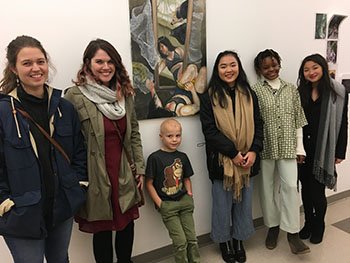 five adults and one child standing next to wall hung artwork