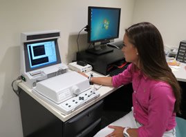 A graduate student operates the Audioscan Hearing Aid Analyzer, used to fit hearing aids. 