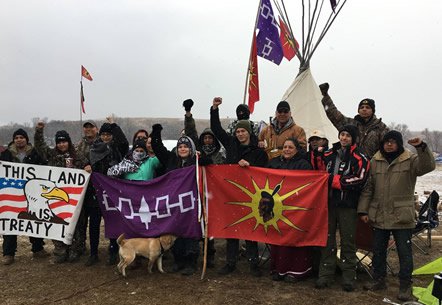 Members of Central New York's Haudenosaunee Confederacy pose at Standing Rock, holding their signature purple flag. (Photo by Kacey Chopito)