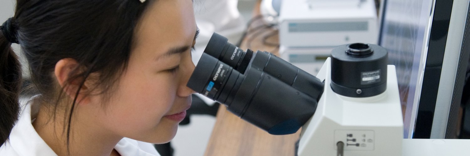 female student looking through microscope oculars.